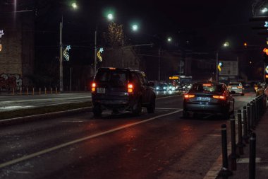 Gece Bükreş 'teki şehir sokak sahnesinde otomobil ışıkları ve boş şehir yolları yer alıyor