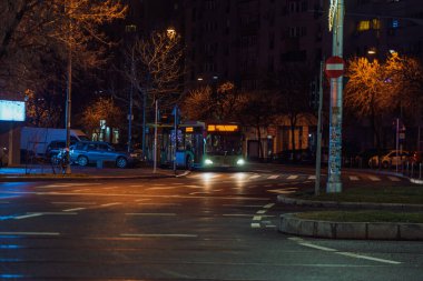Gece Bükreş 'teki şehir sokak sahnesinde otomobil ışıkları ve boş şehir yolları yer alıyor