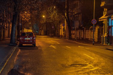 Gece Bükreş 'teki şehir sokak sahnesinde otomobil ışıkları ve boş şehir yolları yer alıyor