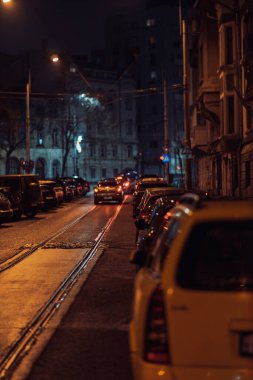 Gece Bükreş 'teki şehir sokak sahnesinde otomobil ışıkları ve boş şehir yolları yer alıyor