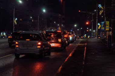 Gece Bükreş 'teki şehir sokak sahnesinde otomobil ışıkları ve boş şehir yolları yer alıyor
