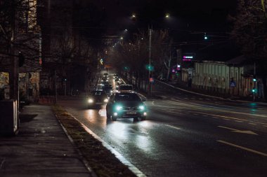 Gece Bükreş 'teki şehir sokak sahnesinde otomobil ışıkları ve boş şehir yolları yer alıyor