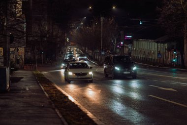 Gece Bükreş 'teki şehir sokak sahnesinde otomobil ışıkları ve boş şehir yolları yer alıyor