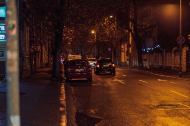 Gece Bükreş 'teki şehir sokak sahnesinde otomobil ışıkları ve boş şehir yolları yer alıyor