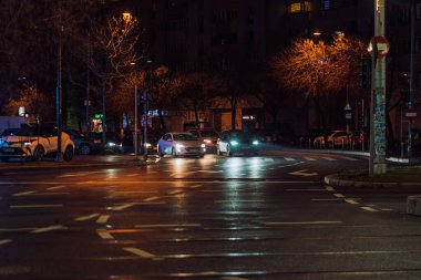 Gece Bükreş 'teki şehir sokak sahnesinde otomobil ışıkları ve boş şehir yolları yer alıyor