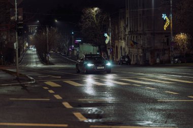 Gece Bükreş 'teki şehir sokak sahnesinde otomobil ışıkları ve boş şehir yolları yer alıyor