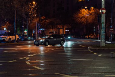 Gece Bükreş 'teki şehir sokak sahnesinde otomobil ışıkları ve boş şehir yolları yer alıyor