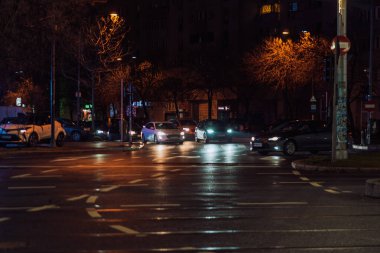 Gece Bükreş 'teki şehir sokak sahnesinde otomobil ışıkları ve boş şehir yolları yer alıyor