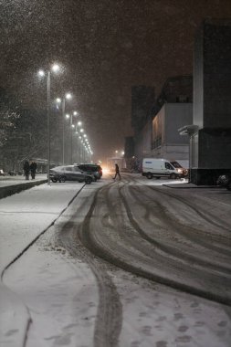 Şiddetli kar yağışı altında, kış havası koşullarıyla şehir sokaklarında yürüyen insanlar.