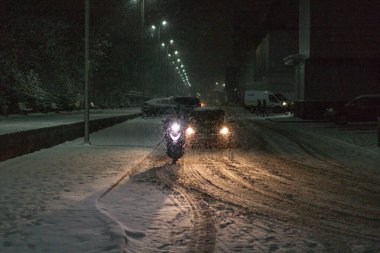 Kışın şiddetli bir kar fırtınası sırasında karla kaplı bir yolda giden araba.
