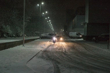 Kışın şiddetli bir kar fırtınası sırasında karla kaplı bir yolda giden araba.