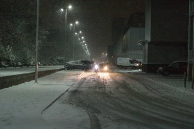 Kışın şiddetli bir kar fırtınası sırasında karla kaplı bir yolda giden araba.