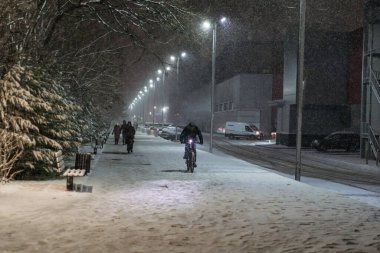 Şiddetli kar yağışı altında, kış havası koşullarıyla şehir sokaklarında yürüyen insanlar.