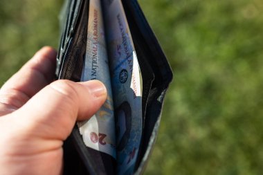 Romen LEI banknotlarıyla el ele tutuşan adamın elinde kağıt doku ve Rumen LEI para birimi sembolleri görülüyor