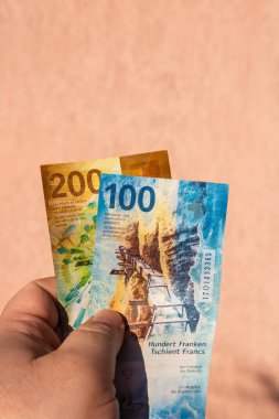 İsviçre frangı para banknotlarını tutan adam, İsviçre CHF para biriminin kağıt dokusu ve sembollerini gösteriyor