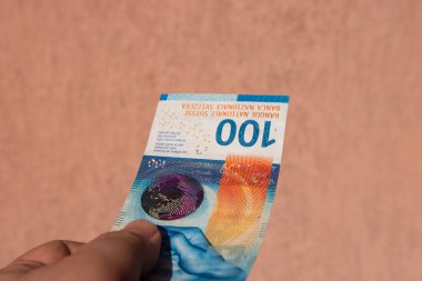 İsviçre frangı para banknotlarını tutan adam, İsviçre CHF para biriminin kağıt dokusu ve sembollerini gösteriyor