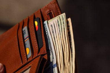 Amerikan dolarının kağıt dokusu ve sembollerini gösteren ABD Doları banknotlarıyla el ele tutuşan adam.