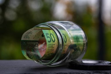 İsviçre frangı CHF banknotu cam kavanozda para biriktiriyor. Tüketim ve ekonomi. İş, bahşiş, finans, tasarruf, bankacılık ve insan kavramı