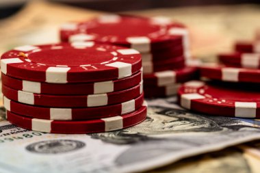 Amerikan dolarları üzerine yığılmış poker fişleri ve kumarhaneyi temsil eden kâğıtlar ve riskler