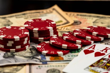 Amerikan dolarları üzerine yığılmış poker fişleri ve kumarhaneyi temsil eden kâğıtlar ve riskler