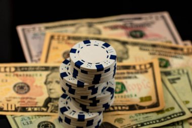 Amerikan dolarları üzerine yığılmış poker fişleri ve kumarhaneyi temsil eden kâğıtlar ve riskler