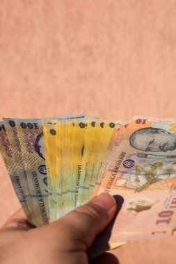 Romen para banknotlarını tutan, kağıt doku ve Rumen LEI para biriminin sembollerini gösteren bir adam.