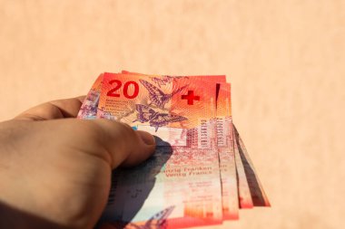 İsviçre frangı para banknotlarını tutan adam, İsviçre CHF para biriminin kağıt dokusu ve sembollerini gösteriyor