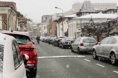 Kış boyunca Bükreş 'in yoğun bir caddesinde yoğun trafikte arabaları kar kapladı