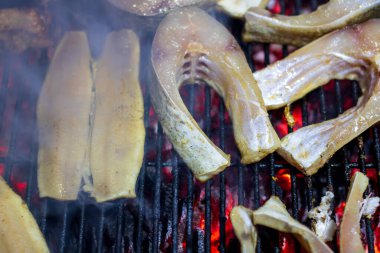 Sıcak ızgarada pişen taze balık filetoları. Sağlıklı açık hava pikniği için duman ve ateş alevleri.