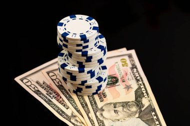Amerikan dolarları üzerine yığılmış poker fişleri ve kumarhaneyi temsil eden kâğıtlar ve riskler