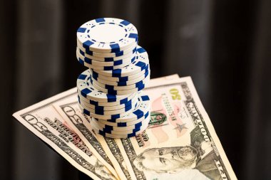 Amerikan dolarları üzerine yığılmış poker fişleri ve kumarhaneyi temsil eden kâğıtlar ve riskler