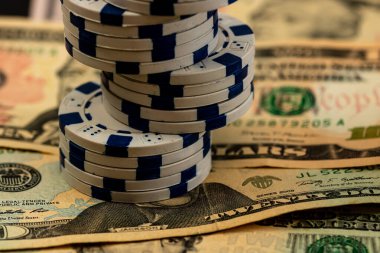 Amerikan dolarları üzerine yığılmış poker fişleri ve kumarhaneyi temsil eden kâğıtlar ve riskler