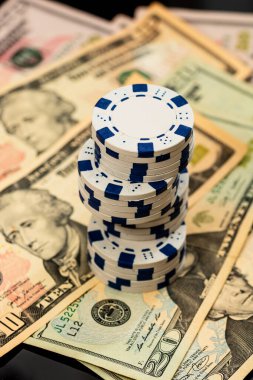 Amerikan dolarları üzerine yığılmış poker fişleri ve kumarhaneyi temsil eden kâğıtlar ve riskler