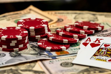 Amerikan dolarları üzerine yığılmış poker fişleri ve kumarhaneyi temsil eden kâğıtlar ve riskler