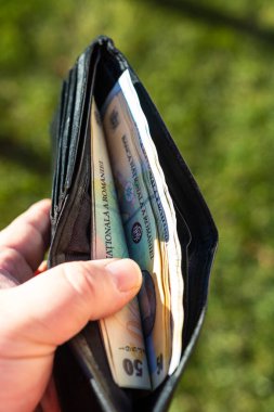 Romen LEI banknotlarıyla el ele tutuşan adamın elinde kağıt doku ve Rumen LEI para birimi sembolleri görülüyor