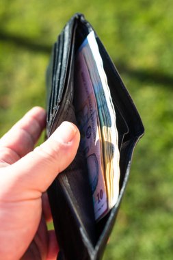 Romen LEI banknotlarıyla el ele tutuşan adamın elinde kağıt doku ve Rumen LEI para birimi sembolleri görülüyor