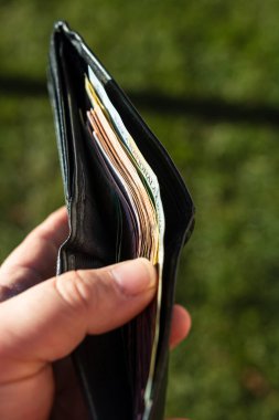 Romen LEI banknotlarıyla el ele tutuşan adamın elinde kağıt doku ve Rumen LEI para birimi sembolleri görülüyor