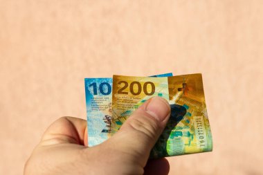 İsviçre frangı para banknotlarını tutan adam, İsviçre CHF para biriminin kağıt dokusu ve sembollerini gösteriyor