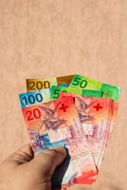 İsviçre frangı para banknotlarını tutan adam, İsviçre CHF para biriminin kağıt dokusu ve sembollerini gösteriyor