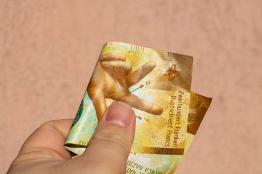 İsviçre frangı para banknotlarını tutan adam, İsviçre CHF para biriminin kağıt dokusu ve sembollerini gösteriyor