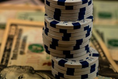 Amerikan dolarları üzerine yığılmış poker fişleri ve kumarhaneyi temsil eden kâğıtlar ve riskler