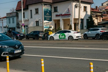 Bükreş 'te güneşli bir bahar gününde yoğun bir şehir caddesinde trafik ve trafik sıkışıklığında bekleyen banliyö araçları görülüyor