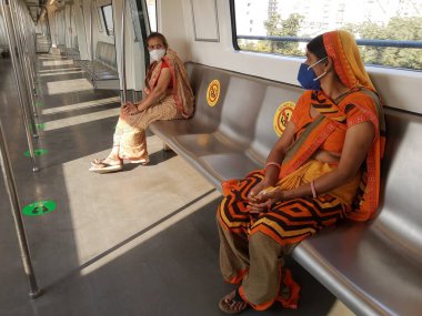 Delhi, INDIA - 28 Ekim 2020: Yolcular, Covid-19 Coronavirus salgını nedeniyle metro şebekesi kapandıktan sonra metroda seyahat ederken maske takıyor.