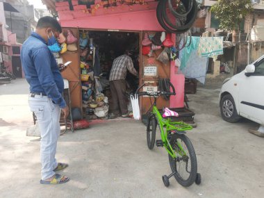 Delhi, Hindistan - Haziran 05, 2021: Bisiklet tamircisi yol kenarındaki dükkanında tamirat yaptı