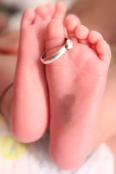Eheringe Den Kleinen Beinen Eines Neugeborenen — Stockfoto