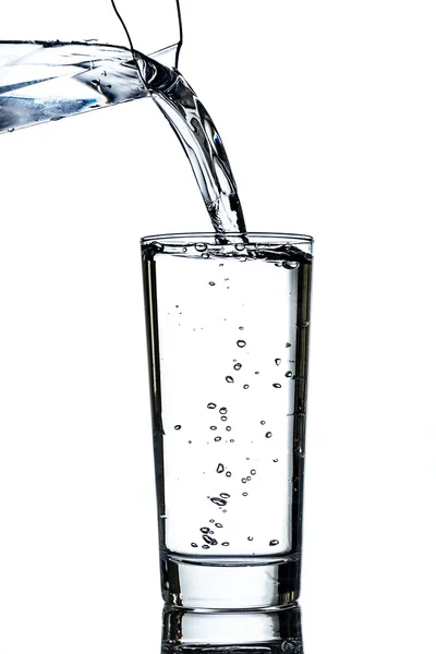 Sauberes Wasser aus einem Krug in ein Glas gegossen — Stockfoto