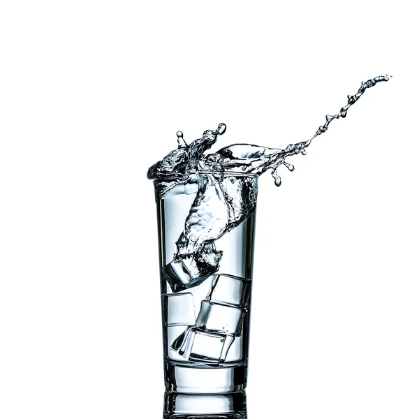 Il cubetto di ghiaccio cade in vetro d'acqua all'atto di causa uno schizzo — Foto Stock