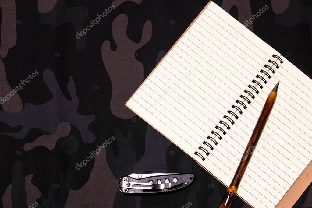 Hunting background. Blank notepad on a military camouflage background. Place for text. Flat lay, top view. hunting concept, military background.