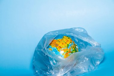 Ekoloji kavramı. Mavi arka planda plastik ambalajlı bir dünya. Plastik atık çevre kirliliği kavramı. Metin için yer.