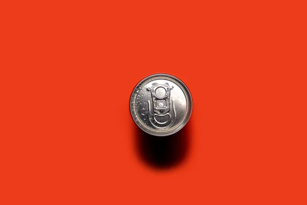 Aluminum can on a red-orange background, with drops of water, a can of soda or beer, top view.